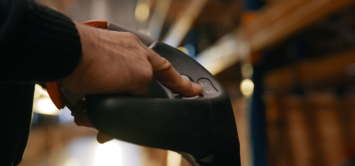 Close-up of a warehouse worker’s hands controlling an MP20X low-lift pallet truck