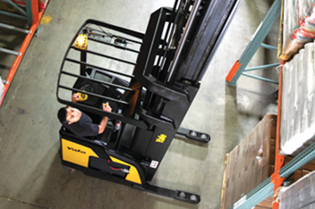 Reach truck operator looking up as he retrieves an item from a high rack