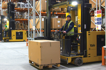 Turret truck operator moves a loaded pallet in a warehouse