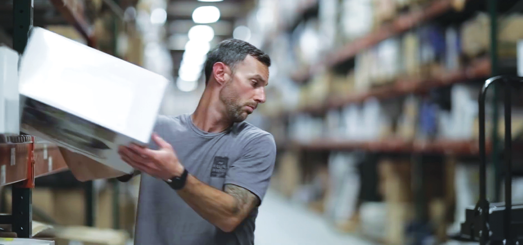 Warehouse worker moves a box from a warehouse rack to a lift truck