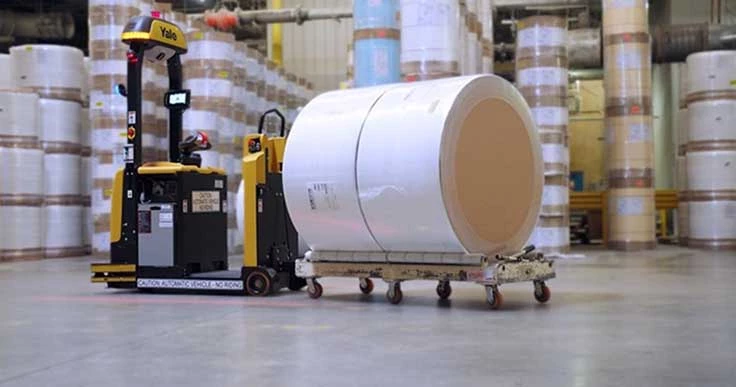 Yale Relay automated tow tractor transporting a paper roll on a flatbed cart